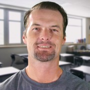 Smiling man with brown hair and a graying mustache and goatee